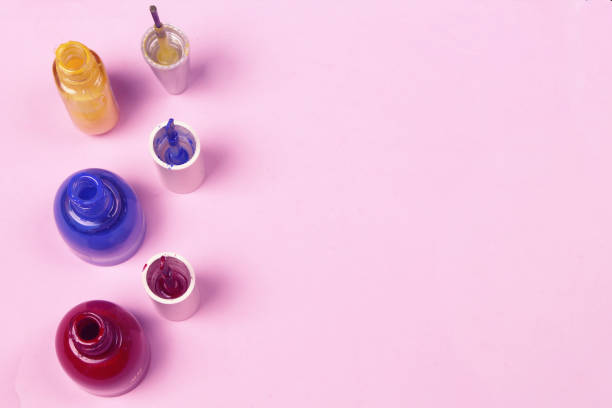 istock Blue, red, yellow nail lacquer  polish bottles and nail brushes on pink background. Copy space for text 1140561449