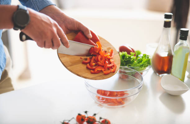 istock Man putting sliced red pepper to bowl while cooking dinner 1140563999