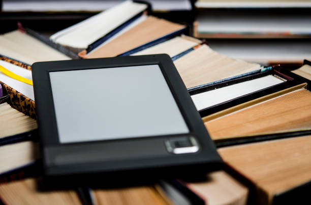istock The e-book with a white screen lies on the open multi-colored books that lie on a dark background, close-up 1140565531