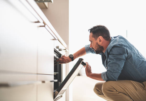 istock Young bearded man checking readiness of dish at oven 1140566421