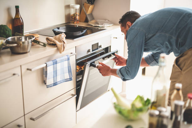 Young man cooking meat in oven at home