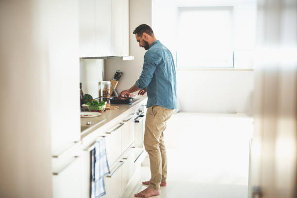Young bearded man cooking dinner at cozy kitchen