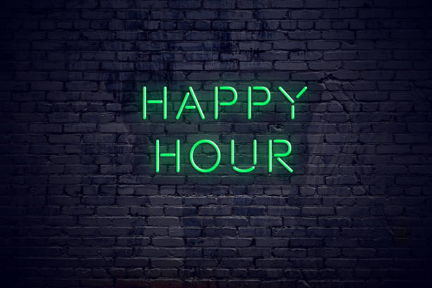 Brick wall at night with neon sign happy hour stock photo