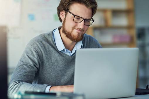 Shot of a young businessman using a laptop in a modern office