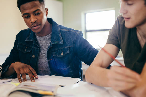 istock University students studying with books in library 1140572559