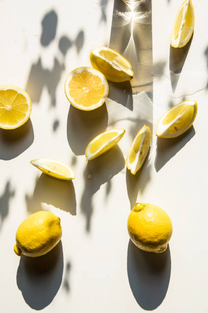 Fresh lemon slices on a table with trendy artistic shadows in the morning sunlight. stock photo