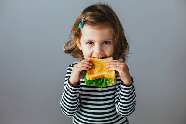 girl having breakfast Portrait of little girl eating sandwich for breakfast at home sandwich healthy lifestyle healthy eating bread stock pictures, royalty-free photos & images