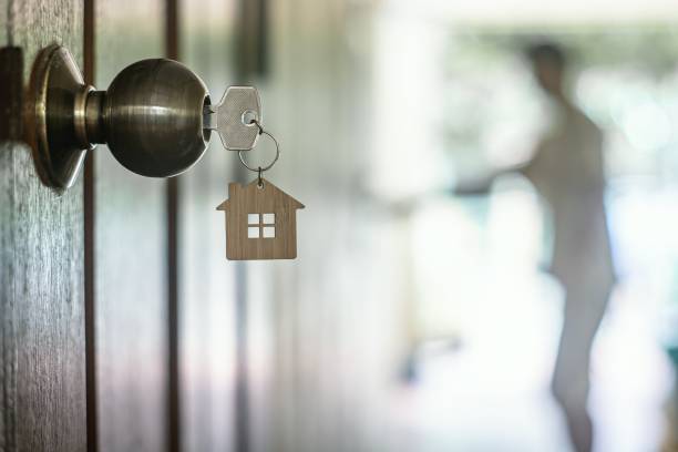 chiave della casa con portachiore a casa nel buco della serratura sulla porta in legno, spazio di copia - casa in affitto foto e immagini stock