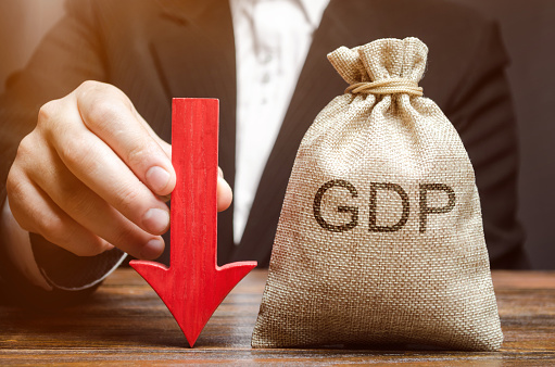 A bag with the word GDP and a down arrow in the hands of a businessman. Decline and decrease of GDP - failure and breakdown of economy and finances leading to financial crisis and trouble. Drop