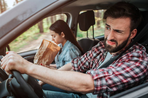 Couple is driving in car. Girl feels sick. She is vomiting into paper bag. Guy feels disgustion. He is not looking at girl. Couple is driving in car. Girl feels sick. She is vomiting into paper bag. Guy feels disgustion. He is not looking at girl puke green color stock pictures, royalty-free photos & images