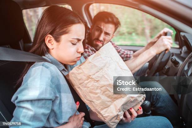 A Picture Of Sick Girl Holding A Bag And Trying To Vomit Into It She Feels Bad Girl Is Holding Her Hand On Stomach Guy Is Looking At Her With Sight Full Of Disgution Stock Photo - Download Image Now
