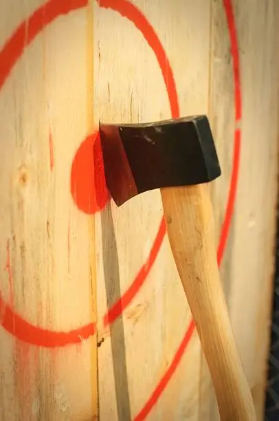A throwing axe stuck in the middle of a wooden target