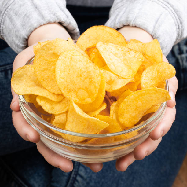 istock Female hand giving crispy potato chips bowl 1140588054