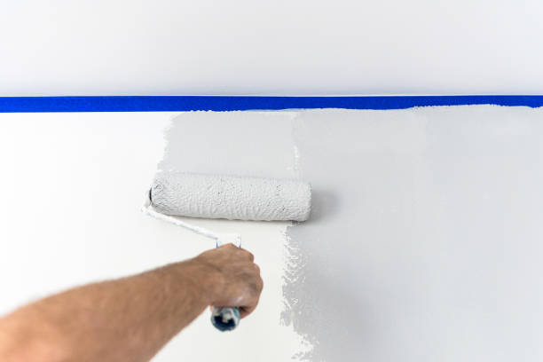 istock Hand painting wall with roll in grey color using blue paint tape 1140588133