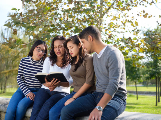istock Mother and young people sitting and reading book 1140590636