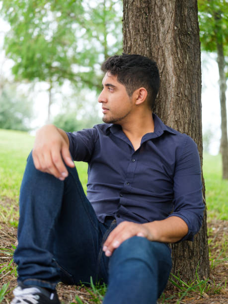 istock Young man leaning on tree and looking away 1140590719