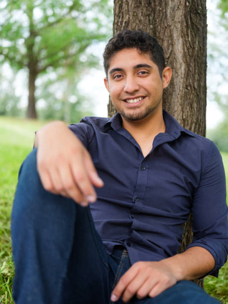 istock Latin young man leaning on tree and smiling 1140590739