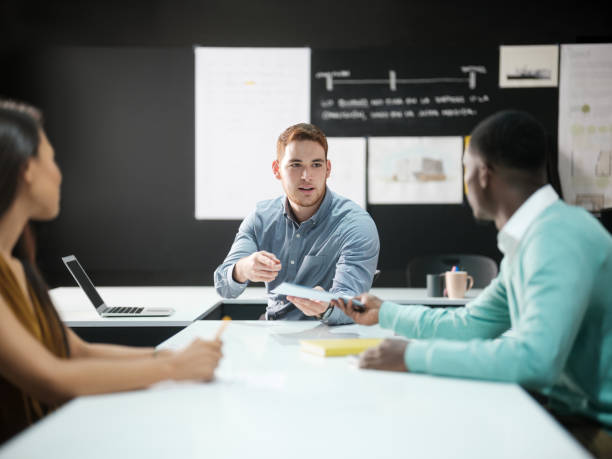istock Young male professional passing papers to coworker 1140596444
