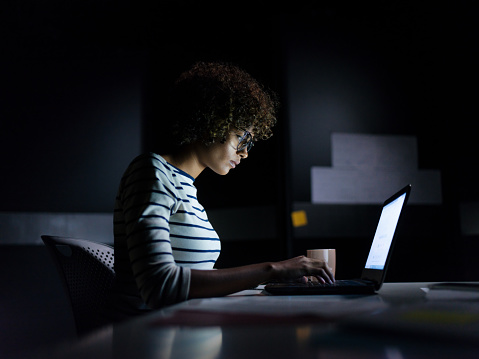 Mujer de negocios concentrada trabajando hasta tarde con su Laptop photo
