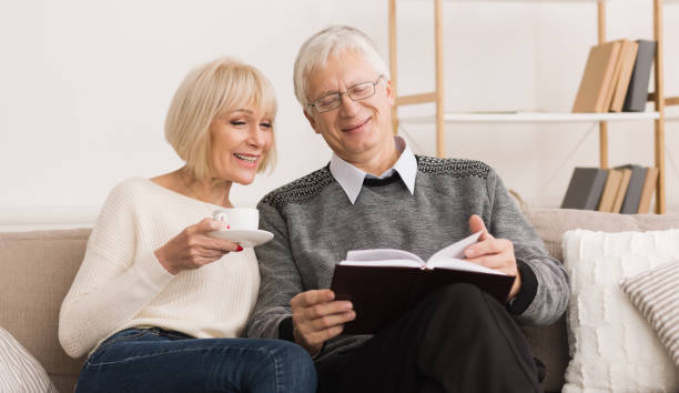 istock Senior couple reading book on couch at home 1140602911