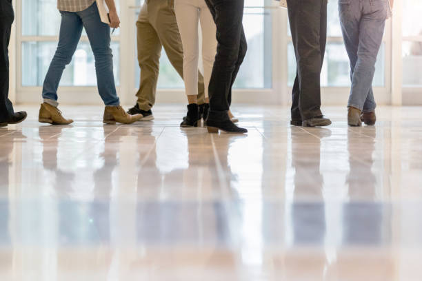 Unrecognizable group of people walk in an office lobby. Only their legs are seen in the photo.