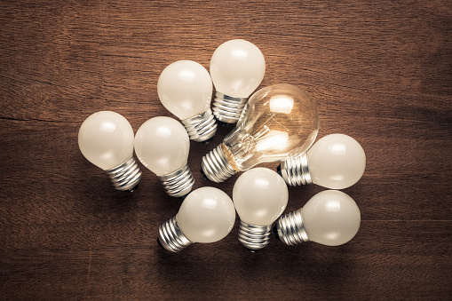 Bigger light bulb glowing among the group of small light bulbs, influencer or success leader with follower concept