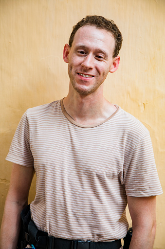 A front-view portrait shot of a mid-adult caucasian man who is visually impaired, he is smiling and looking at the camera.