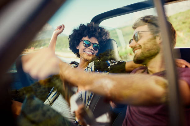 Pareja disfrutando de un viaje por carretera en un coche convertible - foto de stock