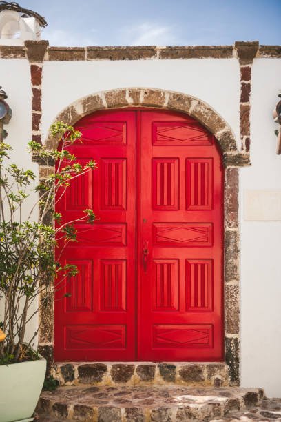 A striking red double door contrasted beautifully against a white architectural facade, showcasing classic design elements and symmetry. Perfect representation of elegance and historical urban charm.
