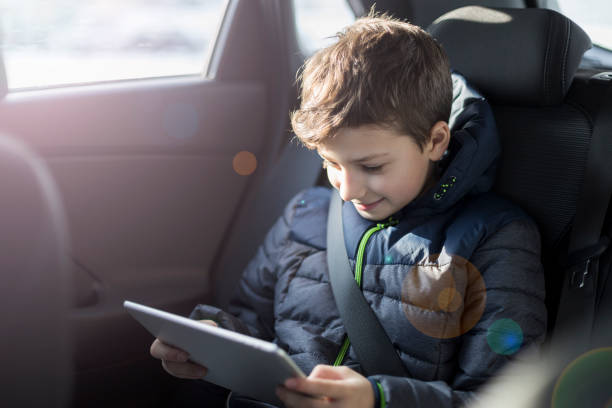 istock Young boy sitting in a car and reading his ebook 1140618185