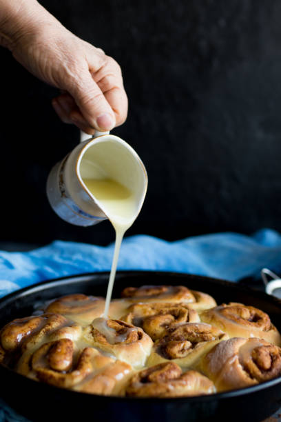 istock Baker putting sugar glaze syrup on to baked cinnamon buns 1140623621