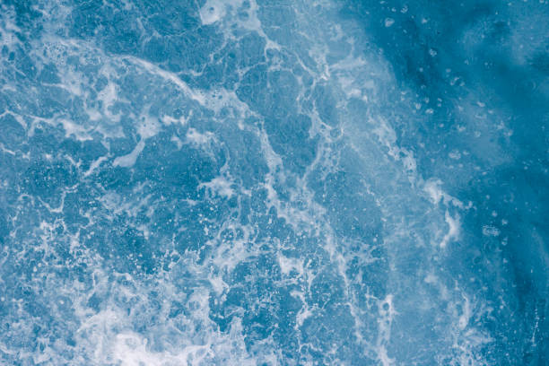 istock Pale blue sea surface with waves, splash,  foam and bubbles at high tide and surf, abstract background 1140630454