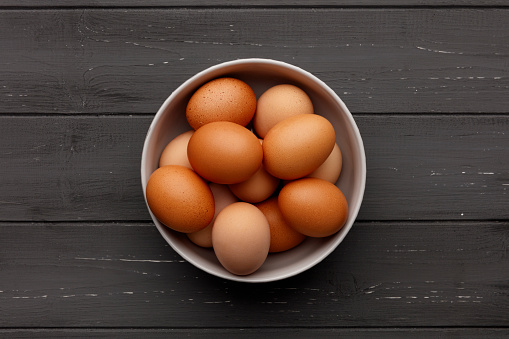 A bowl of fresh eggs on a distressed wooden background, shot from above
