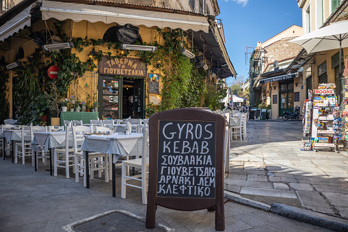 March 31st, 2019, Greece Athens. Greek restaurant taverna at Plaka area, blackboard with daily menu, empty tables and chairs, sunny day