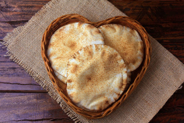 istock Pita bread isolated on white background in the breakfast basket, on rustic wooden table.Traditional and typical food of Arabic cuisine 1140637555