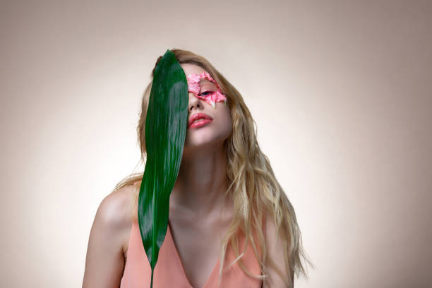 istock Blonde-haired model holding big green leaf near her face 1140638330
