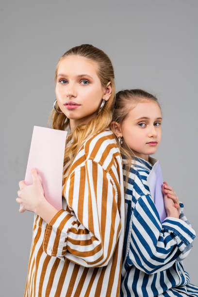 istock Appealing long-haired sisters of different ages standing back to back 1140641690