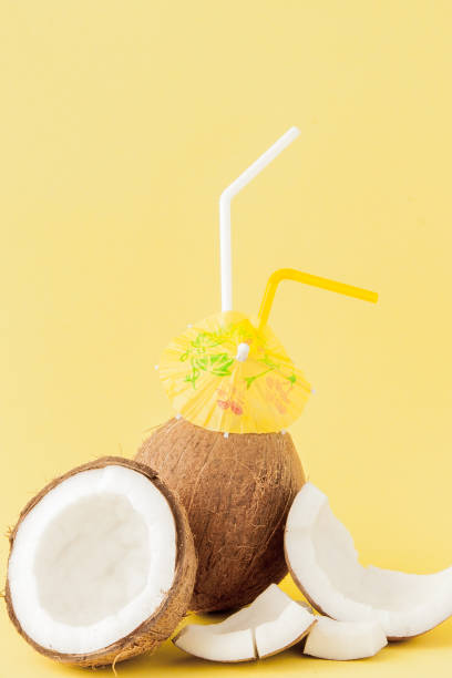 istock Fresh Coconut cocktail with a straws on yellow background 1140643009