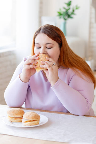 istock Nice plump woman eating a tasty burger 1140647275