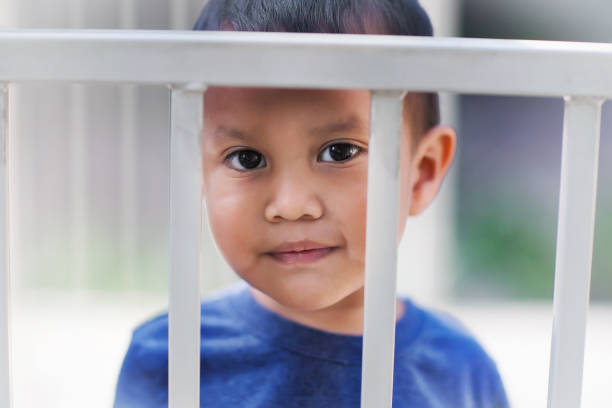 istock Young hispanic boy behind bars from a crib looking sad about getting a time out for bad behavior. 1140649702