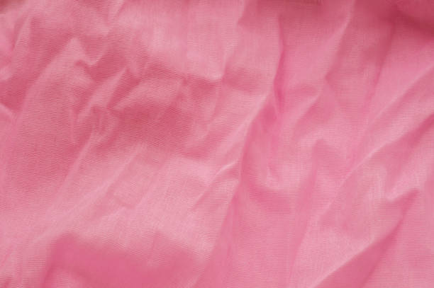 istock Pink background from a textile material with wicker pattern, closeup. Cloth backdrop. Crumpled fabric. Selective focus 1140650093