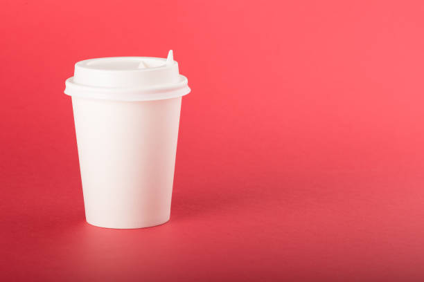 istock White disposable paper cup with white cap on a red background 1140652465