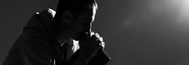 Photo of Religious young man praying to God on dark background, black and white effect