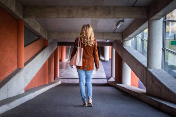Fashionable young woman walking in public car park. Stylish blond hair woman wearing corduroy jacket and jeans. corduroy jacket stock pictures, royalty-free photos & images