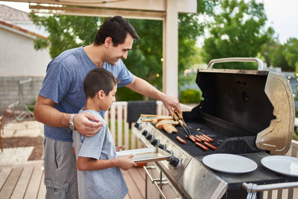 istock father teaching son how to grill hot dogs and bonding 1140662080