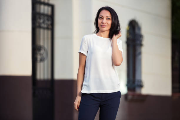 Happy young fashion woman in white t-shirt on city street stock photo