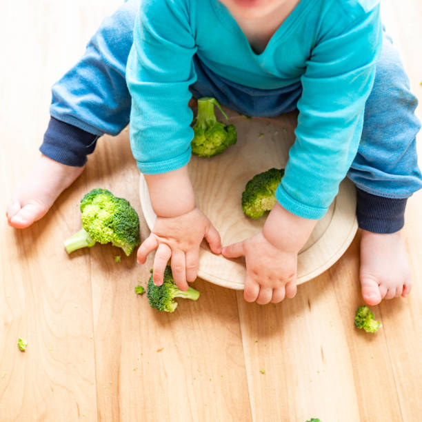 istock Little baby playing with broccoli 1140664128
