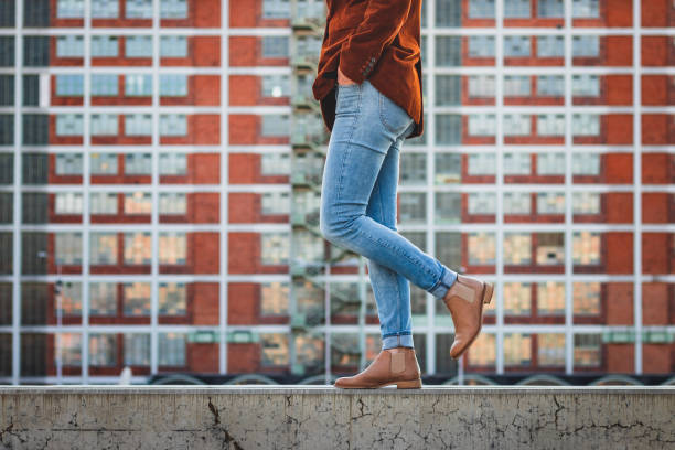 Woman wearing denim pants and stylish leather shoe in city. Modern architecture as background. Concept of beauty and fashion corduroy jacket stock pictures, royalty-free photos & images