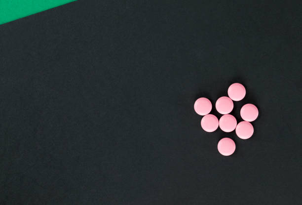 istock black paper and Pink pills 1140676643
