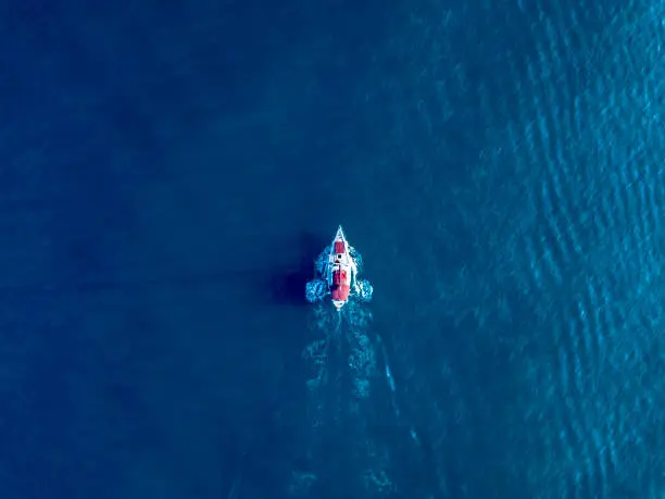 Photo of a lone yacht swim in deep blue ocean top view